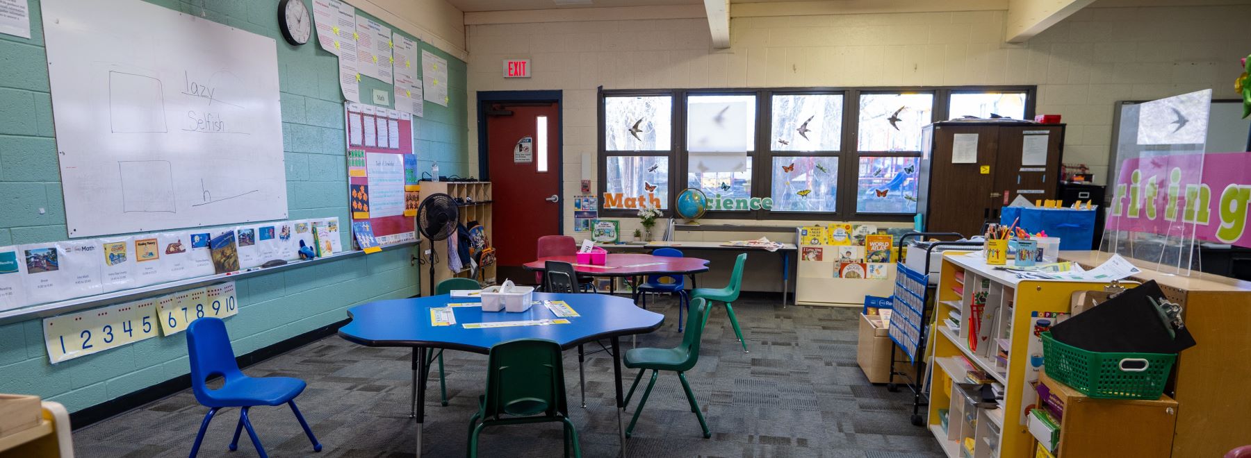 A classroom filled with tables and chairs arranged for students to sit and learn.